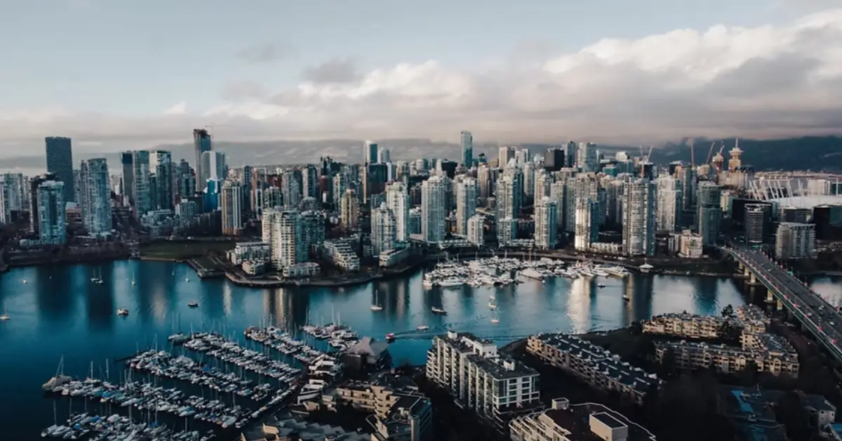 Aerial-view-of-Vancouvers-skyline-showcasing-skyscrapers-a-marina-with-boats-and-serene-waters-under-a-cloudy-sky