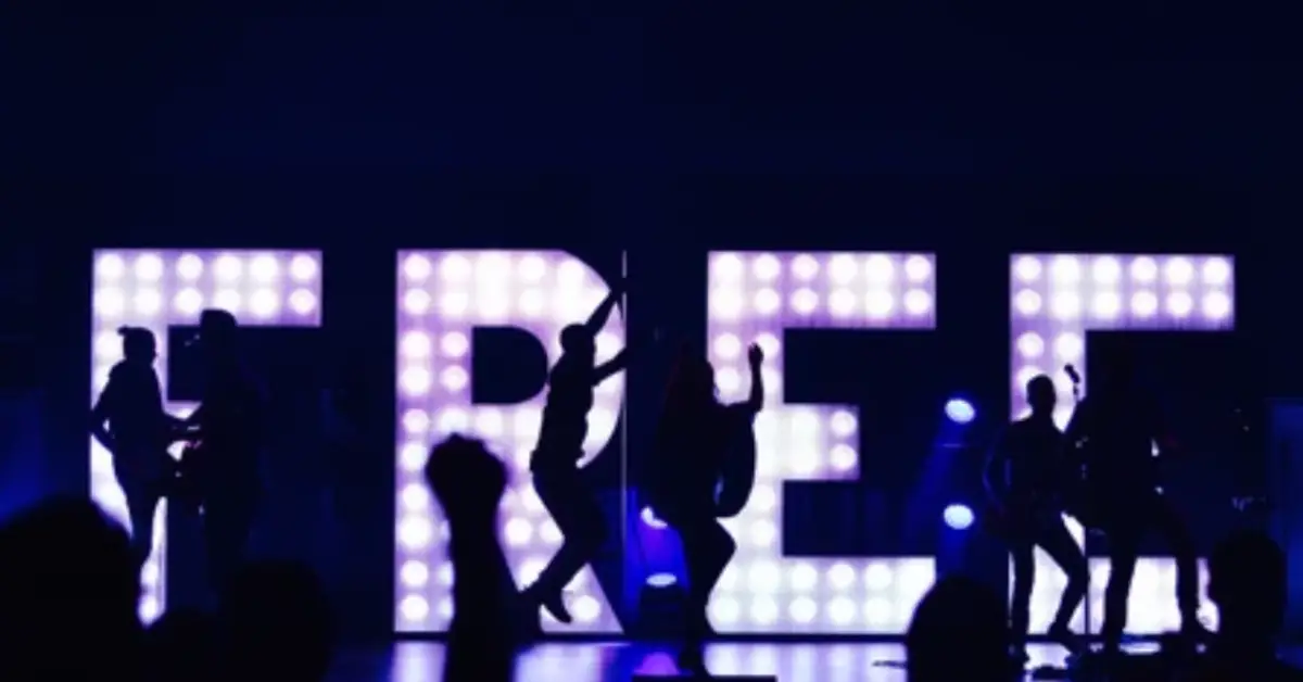 Silhouettes-of-performers-dance-in-front-of-a-large-illuminated-sign-spelling-_FREE_-at-a-concert-creating-a-lively-energetic-atmosphere