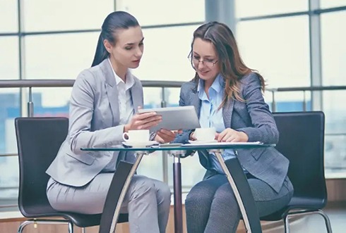 two professionals in suits seated having a discussion with a tablet on a table